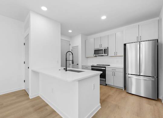 A kitchen with white cabinets and a white island.