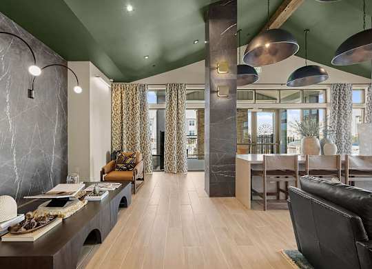 A modern living room with a long wooden table and black leather couch.