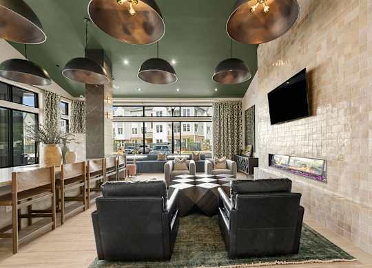 A modern living room with a large black sofa and a flat screen TV mounted on the wall.