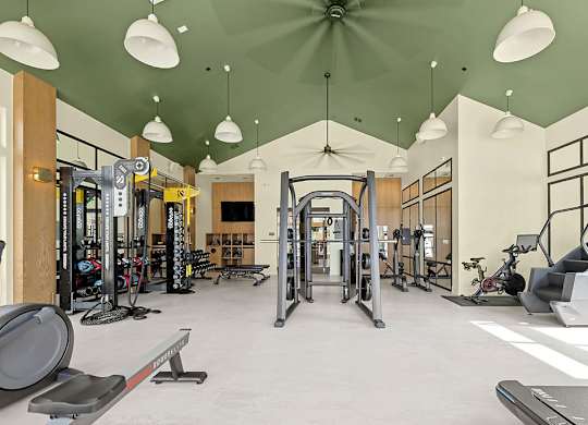 A gym with a variety of equipment including treadmills, weights, and exercise machines.