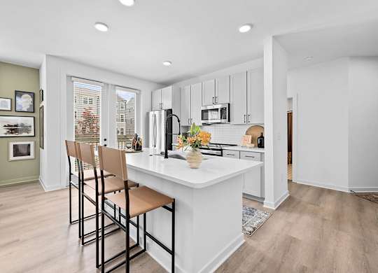A kitchen with a white island and brown barstools.
