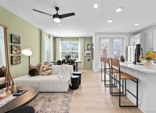 A modern kitchen with a white countertop and bar stools.