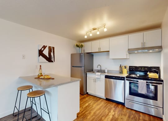 a kitchen with stainless steel appliances and a counter with two stools