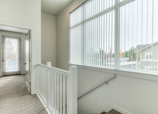 A white room with a carpeted floor and a staircase with white railings.