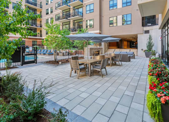 A patio with a table and chairs is surrounded by a fence and buildings.
