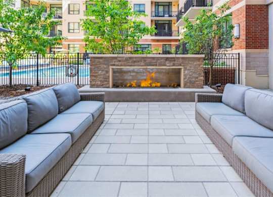 A patio with a grey couch and a fireplace.