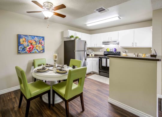 a dining room table and chairs with a kitchen in the background