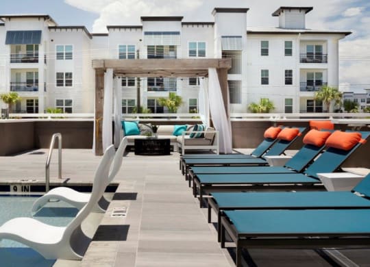 a pool with lounge chairs and a fire pit in front of an apartment building