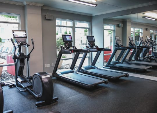 a row of treadmills and ellipticals in a gym