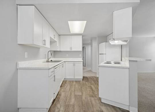 A kitchen with white cabinets and a wooden floor.