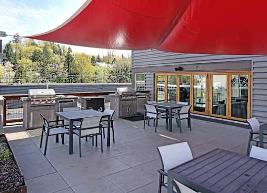 A patio with a table and chairs under a red canopy.