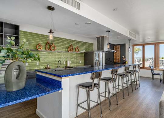 A kitchen with a blue counter top and stools.