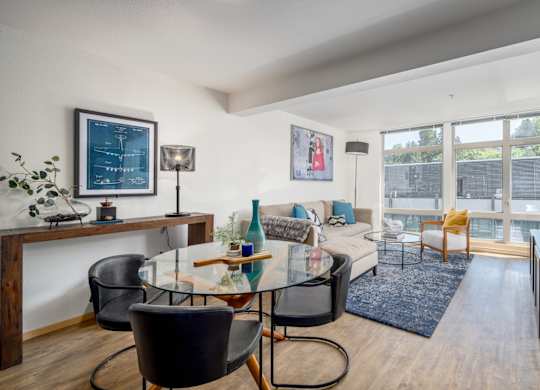 A modern living room with a glass table and black chairs.