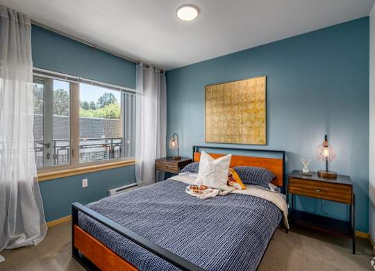 A bedroom with a bed, nightstand, and window.