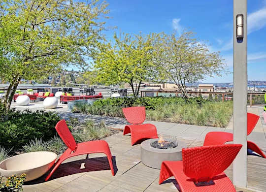 A patio with red chairs and a fire pit.