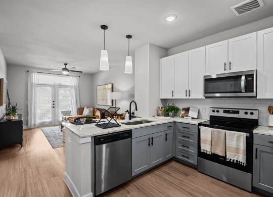 an open kitchen with stainless steel appliances and white cabinets at Lenox Grand, Texas, 78727