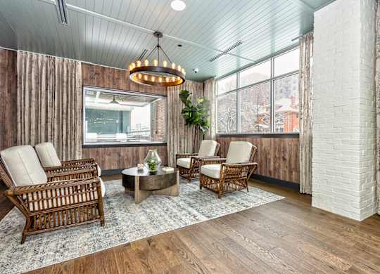 Resident common area with wooden furniture, modern style chandelier, and large windows at Sylvan Uptown, Colorado