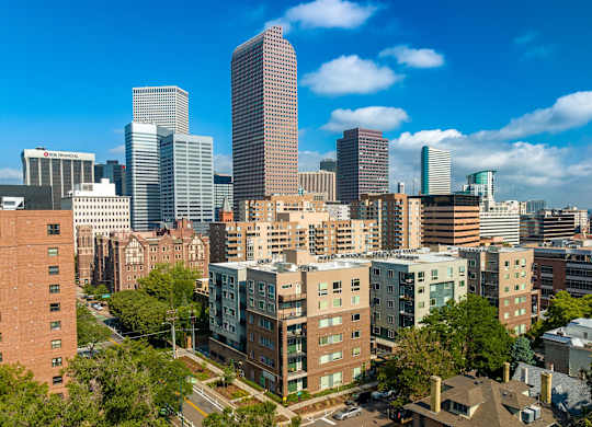 Denver skyline showing the apartment building on a sunny day with blue sky and white clouds at Sylvan Uptown, Denver, CO
