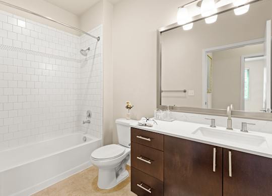 Spacious bathroom with tiled shower, bathtub, and updated vanity area with above-mirror lighting at Sylvan Uptown,Colorado, Denver