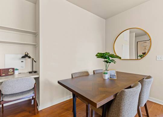 Chic seperate dining room with a patterned wood table next to a small built-in desk with wall shelving and a grey chair at Sylvan Uptown, Denver, CO