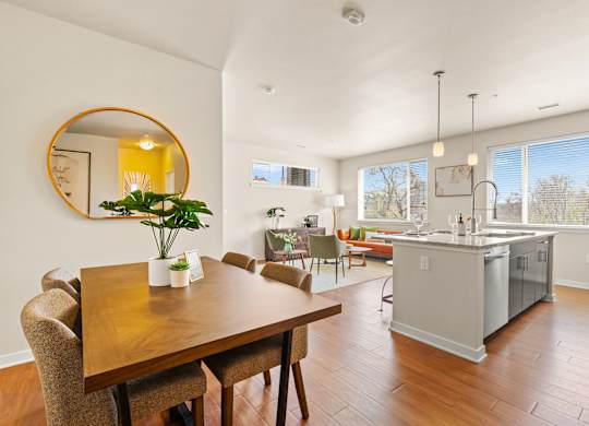 a modern dining room with a wooden table and chairs with a view into the stunning kitchen and luxurious living area at Sylvan Uptown, Denver, CO, 80203
