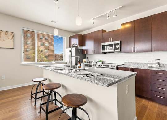 View of the kitchen with a granite island with barstool seating and pendant lighting at Sylvan Uptown, Denver