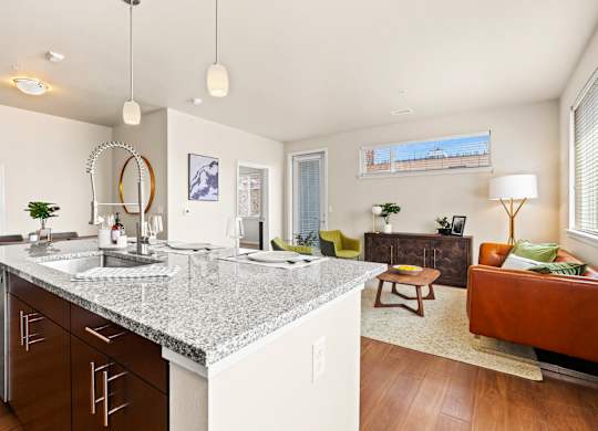 Luxury kitchen with an island with granite counter tops and pendant lighting with a view into the  living room at Sylvan Uptown, Colorado