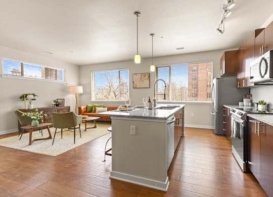 Spacious kitchen with hardwood flooring and an island with view into well-decorated living room at Sylvan Uptown, Colorado, 80203