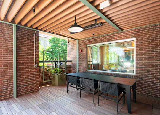 Covered red brick patio with hardwood flooring, a long table and chairs at Sylvan Uptown, Denver, CO, 80203