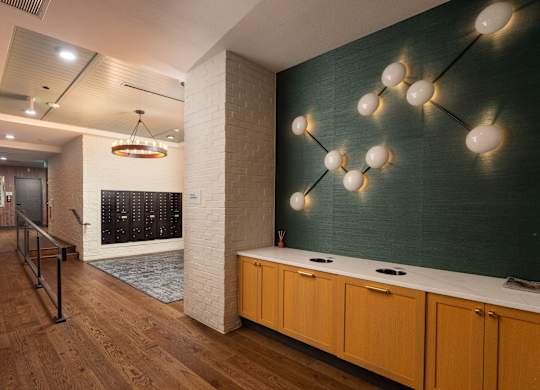 Spacious walkway to the mail area with chic wall decorations on the green wall and modern style chandelier at Sylvan Uptown, Colorado