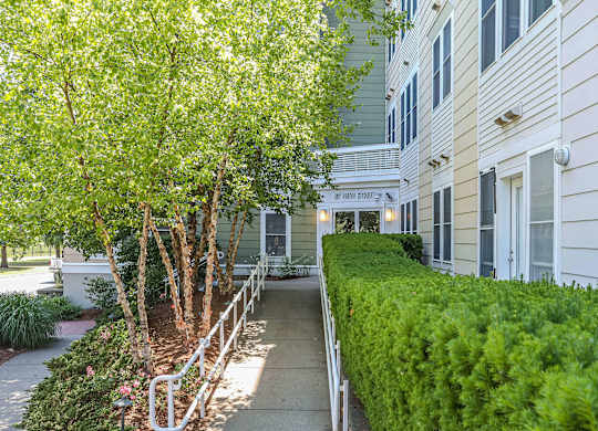 A tree-lined walkway leads to a building with a sign at Park87 Apartments, Cambridge, MA, 02138