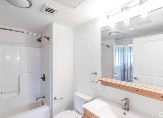 A white bathroom with a toilet, sink, and shower at Park87 Apartments, Cambridge, MA