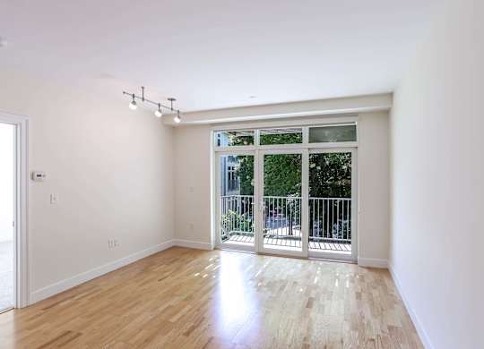A spacious living room with a sliding glass door leading to a balcony at 7 Cameron Apartments, Massachusetts, 02140