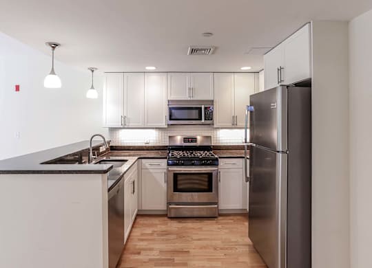 A modern kitchen with stainless steel appliances and wooden floors at 7 Cameron Apartments, Massachusetts, 02140