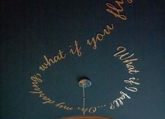 a black wall with writing on it and a lamp
