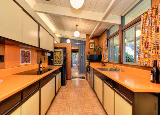 A kitchen with orange countertops and white cabinets.
