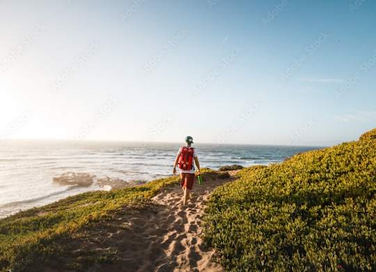 a man walking on a sandy path near the ocean