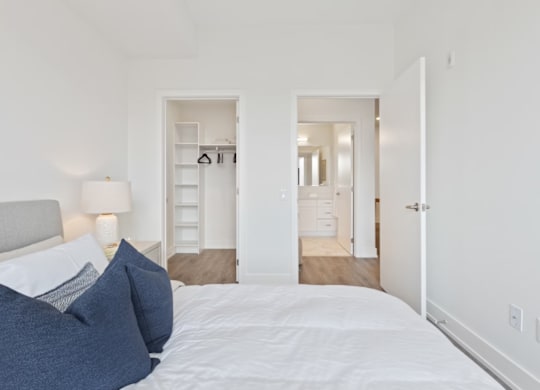 A bedroom with a bed, two lamps, and a dresser.