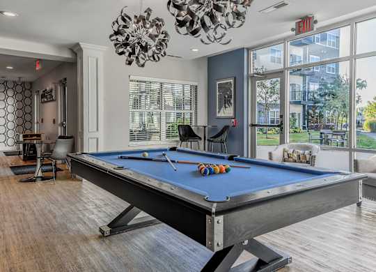 a pool table in a living room with a large window