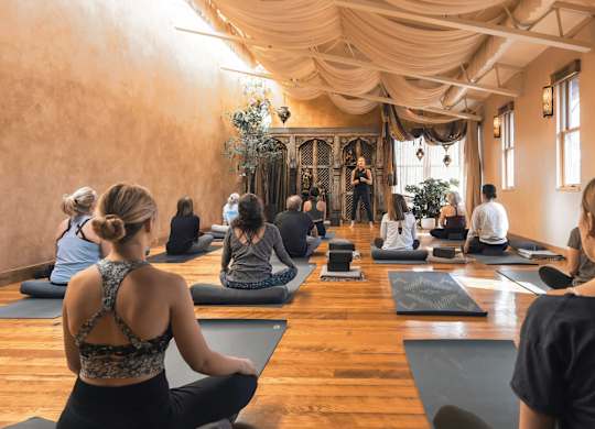 A group of people are sitting on yoga mats in a room.