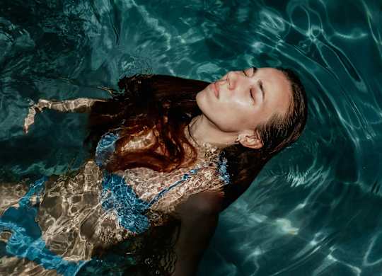 A woman with brown hair is floating in a pool.