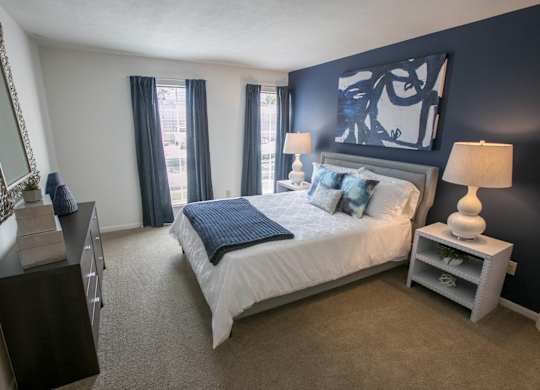 a bedroom with a white bed and blue accent wall carpeted flooring