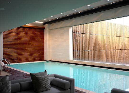 A modern indoor swimming pool with a glass wall.