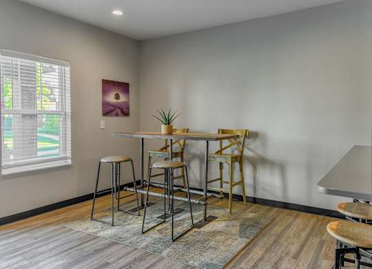 a dining area with a table and chairs and a window