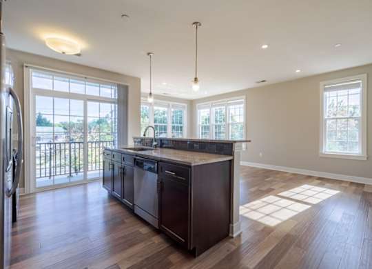 A modern kitchen with dark wood floors and a large island.