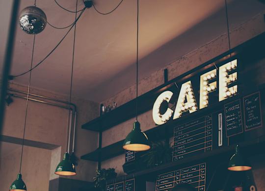 a cafe with a neon sign on the wall