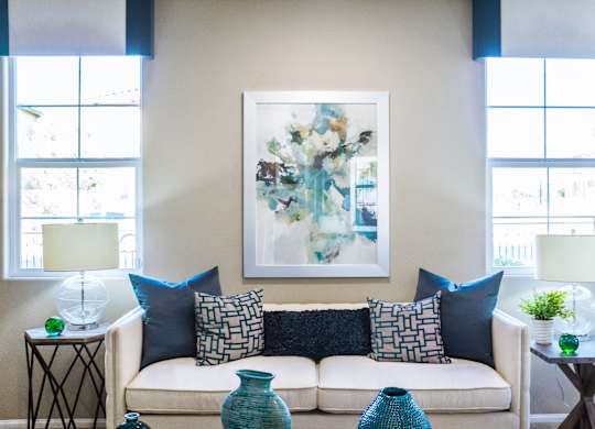 a living room with a couch and pillows and a painting on the wall