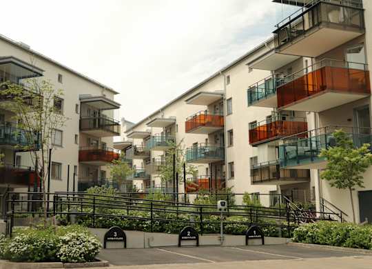 Apartment complex with a black fence and green plants.