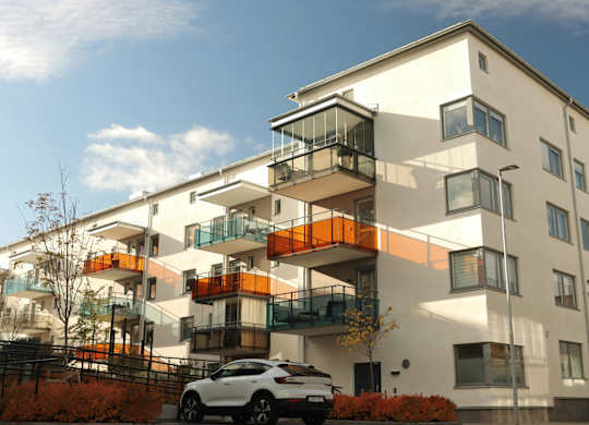A white and orange building with a car parked in front.