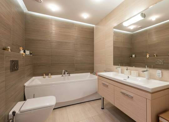 A modern bathroom with a white bathtub and a double sink vanity.